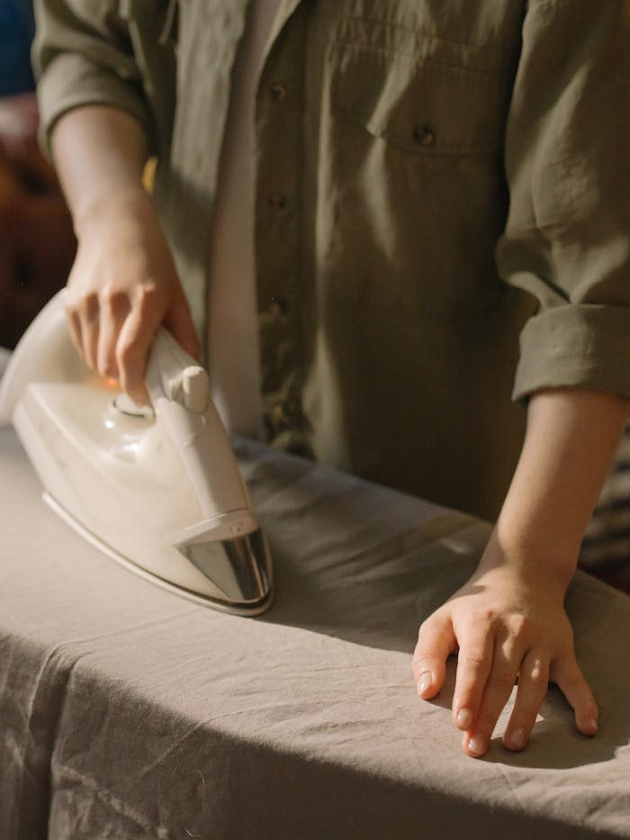 Close-up of a person ironing clothes on an ironing board indoors.